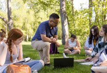 Photo of teacher and students writing outside