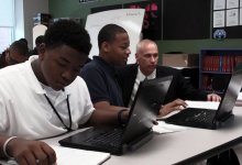 High School students are working on their computers. A teacher is helping them.