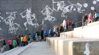 Students and teachers are walking by an art wall.