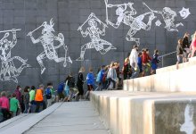 Students and teachers are walking by an art wall.