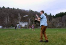 A group of students are hanging out and playing frisbee.