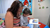 Mom is helping his son with reading in the bedroom.