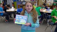 A girl student is presenting her painting.