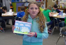 A girl student is presenting her painting.