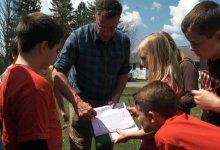 Students and teacher are working together in an outdoor setting.