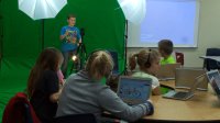 Students are working in a Multimedia class. A student is on a green screen background.