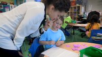 Teacher is looking at a student work in a calssroom.