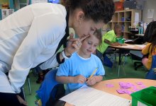 Teacher is looking at a student work in a calssroom.