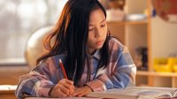 Middle school aged girl studying book in classroom.