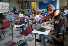 Middle school teacher helps a student at her desk in a hybrid classroom