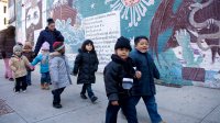 Preschool students walking in pairs on a sidewalk with their teachers