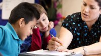 A teacher discusses writing feedback with two students.