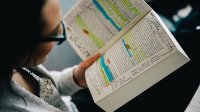 A young woman reads a heavily annotated book.