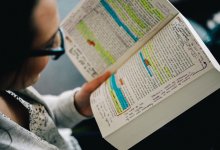 A young woman reads a heavily annotated book.