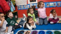 Pre-school children sitting on rug in classroom