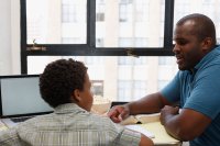 Father and son talking while seated at son's desk