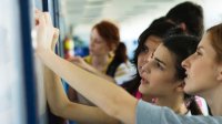 High school students examining work on a bulletin board in a classroom