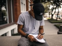 Male student sitting outside writing in a notebook