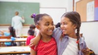 photo of two students smiling at each other in a classroom