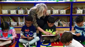 Teacher works with students on reading at Concourse Village.