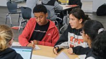 A diverse group of four high school students collaborate at a table at Dayton STEM school