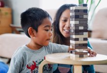 Young boy playing the game Jenga with his mother at home