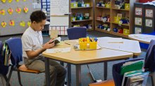 Elementary student reading a book in his classroo