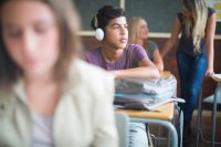 Student wearing headphones listening to music in a classroom