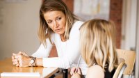 Teacher sitting and talking to elementary student