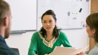 A teacher discusses paperwork with two parents.