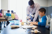 teacher helping hispanic student with science project