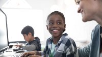 A boy looks up at his teacher with a smile. 