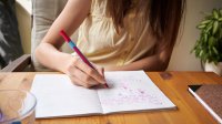 Teenager drawing in a notebook at home