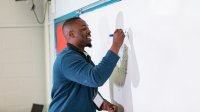 Math teacher writing problems on a whiteboard