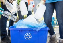 Teenagers dropping plastic bottles into recycling bin