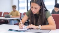 High school student writing at her desk