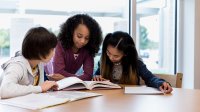 Three middle school students review a textbook together