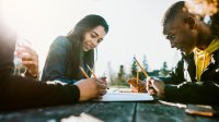 High school students writing outside at a picnic table