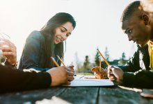 High school students writing outside at a picnic table