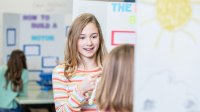 Middle school student explains a science project to an elementary student