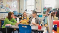 Science teacher working with a small group of elementary students at a table