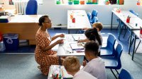 Elementary teacher kneeling down to talk to two students