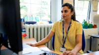 Teacher sitting at her desk and working on her computers