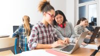 High school students working at laptops