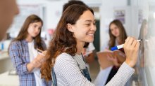 A small group of students work together at a whiteboard