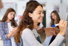 A small group of students work together at a whiteboard