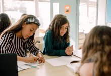 Three middle school students writing and working together at a table in the classroom