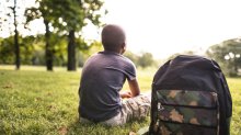 Teenage boy sitting on the grass looking towards horizon