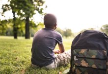 Teenage boy sitting on the grass looking towards horizon