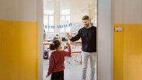 Photo of teacher greeting female student with a high-five at class door